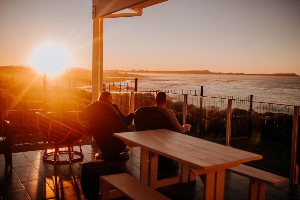 three men sitting at a table watching the sunset at Klipfontein House in Kleinbaai