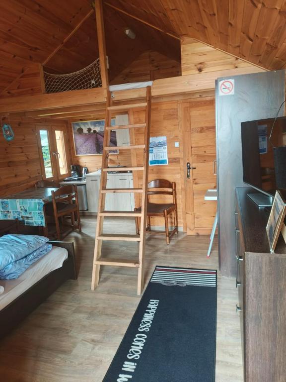 a room with a bunk bed and a ladder in a cabin at Domki letniskowe 30m2 in Nowe Warpno