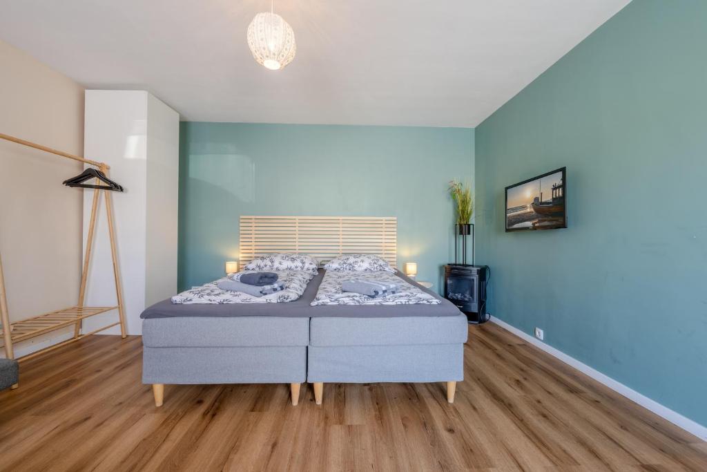 a bedroom with a bed with blue walls and wooden floors at Gemütliche Ferienwohnung - Araliya 2 in Ahlbeck
