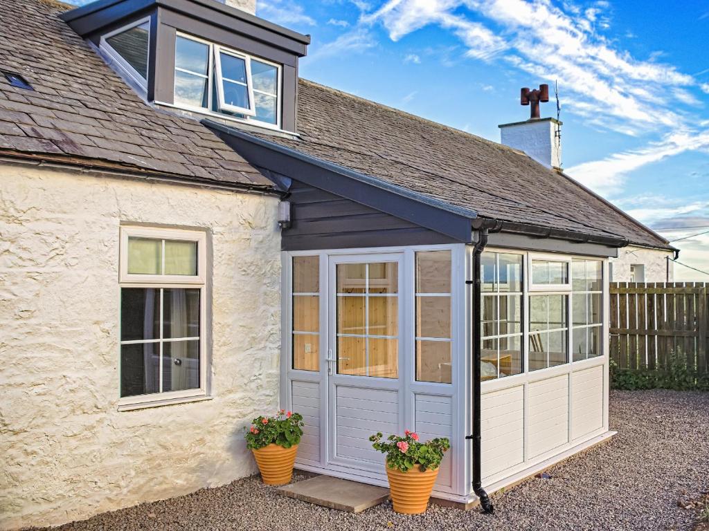 a garage with doors and windows on a house at Arthurs Cottage - Uk51636 in Kirkbean