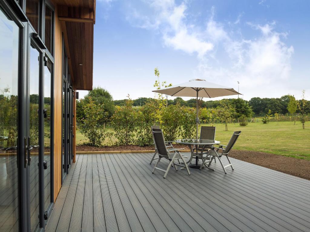 a wooden deck with a table and an umbrella at Oak Lodge in Hassocks