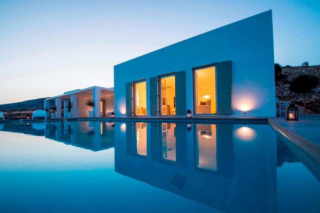 a blue house with a swimming pool at night at villa zakintos in Aspro Chorio Paros