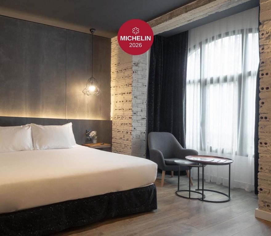 a bedroom with a bed and a desk and a chair at Hotel Tayko Bilbao in Bilbao