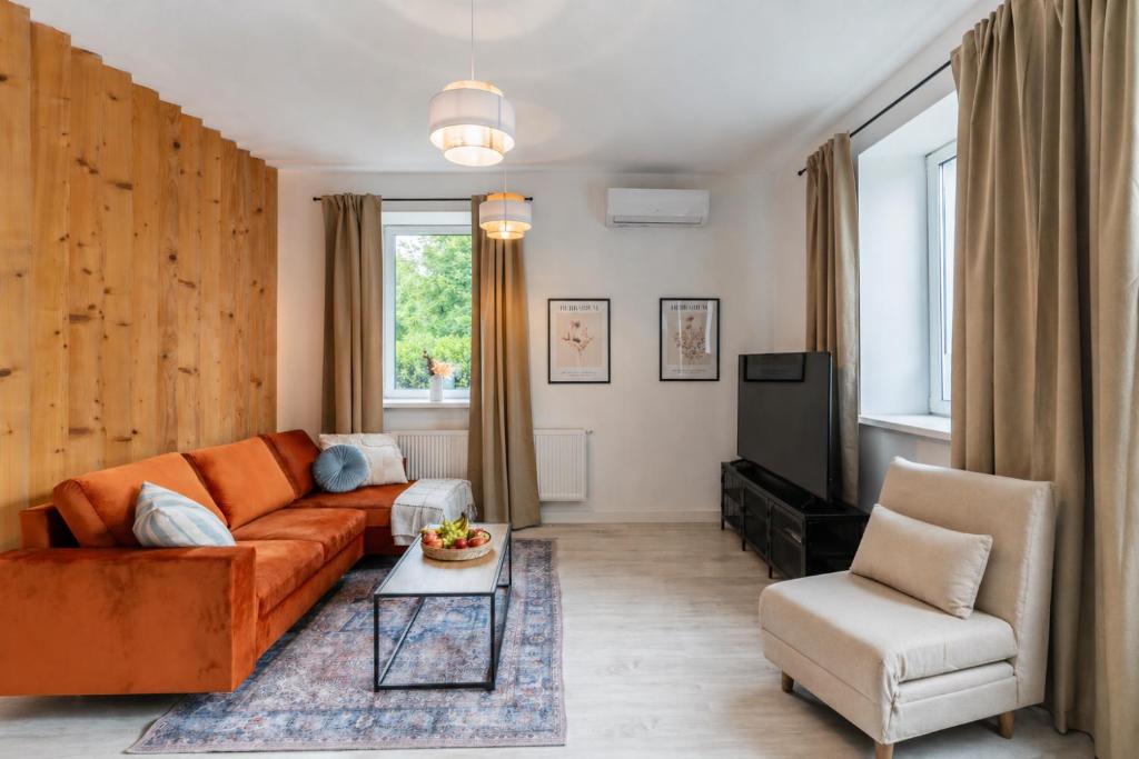 a living room with an orange couch and a tv at Apartment Quiet Street 11/1E in Oświęcim