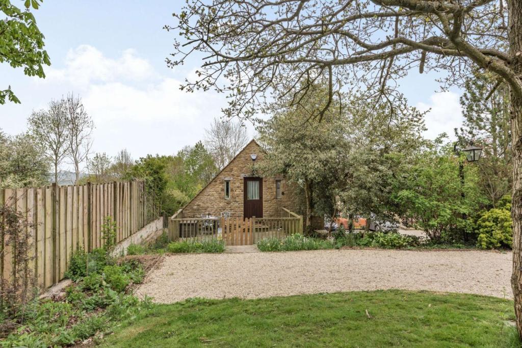 a stone house with a fence and a yard at Rainbow Barns in Bourton on the Water