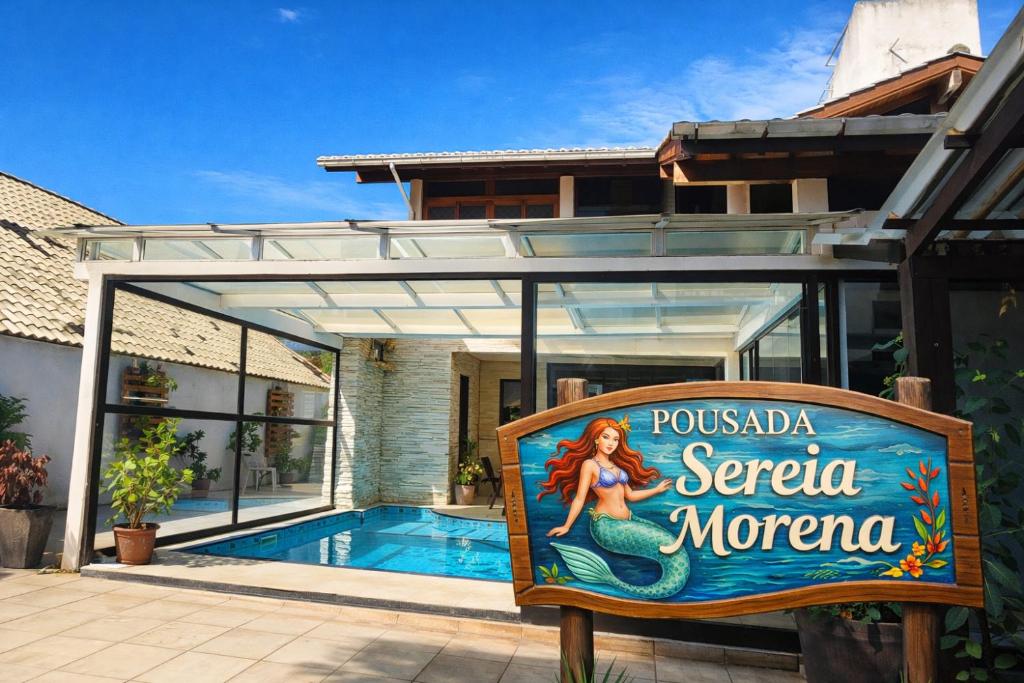 a sign in front of a house with a swimming pool at Pousada Sereia Morena in Florianópolis