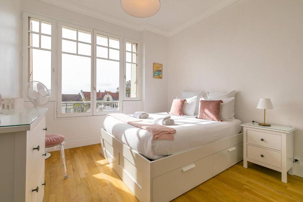 a white bedroom with a large bed and a window at Le Victor Hugo in Dijon
