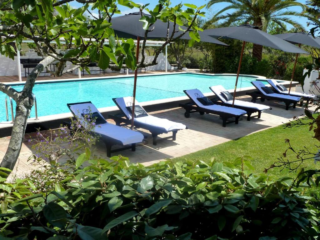 a swimming pool with lounge chairs and umbrellas next to it at Quinta da Lua in Tavira