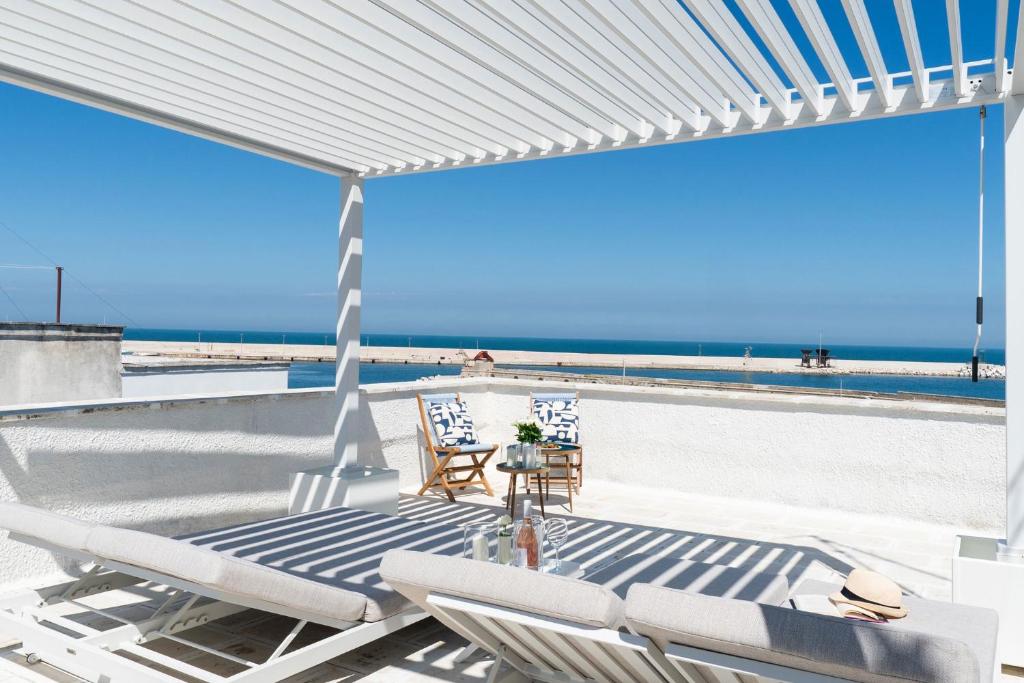 a patio with chairs and a view of the beach at Infinito Luxury by BarbarHouse in Monopoli