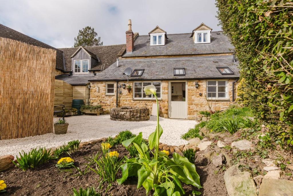 an old stone house with a garden in front of it at Ringers Cottage in Kingham