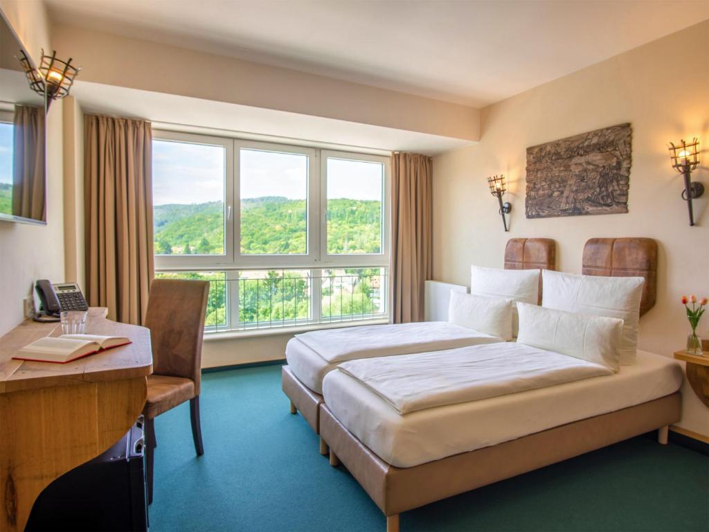 a hotel room with a bed and a desk and window at Hasseröder Burghotel in Wernigerode
