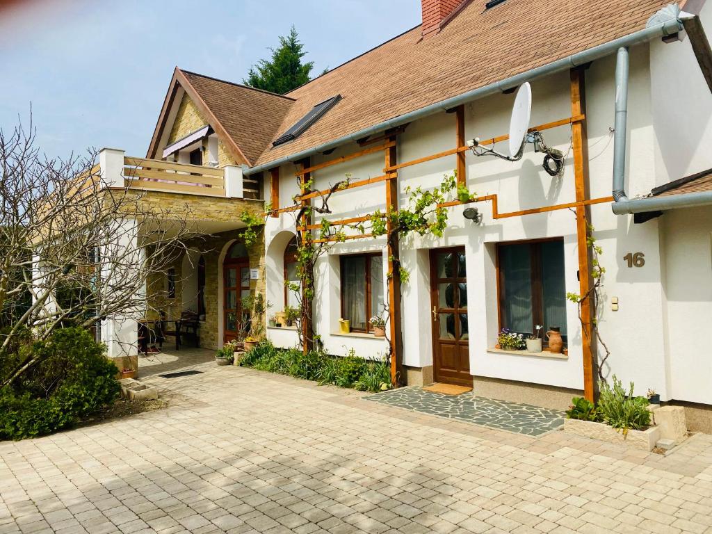 a white house with a brick driveway at Dorka vendégház in Kehidakustány