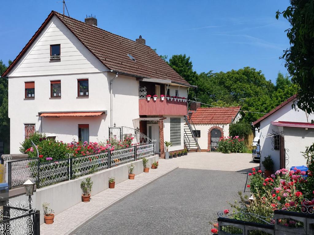 a white house with flowers on a driveway at Ferienhaus Richard in Eschwege
