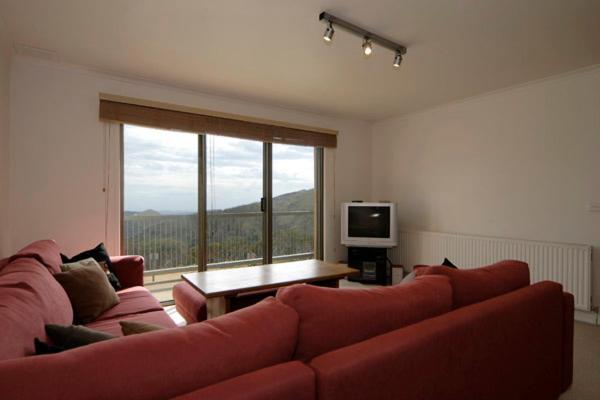 een woonkamer met een rode bank en een groot raam bij Lawlers 9 in Mount Hotham