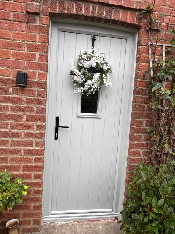 a white door with a window and a wreath on it at Holly Berry Cottage in Holme next the Sea