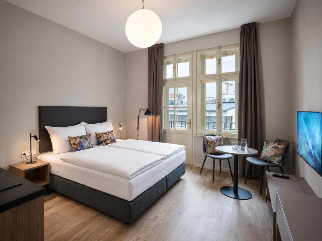 a bedroom with a bed and a table and a tv at Franz BY ZEITRAUM in Prague
