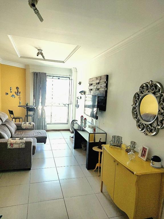 a living room with a couch and a mirror at Apartamento em Guarapari in Guarapari