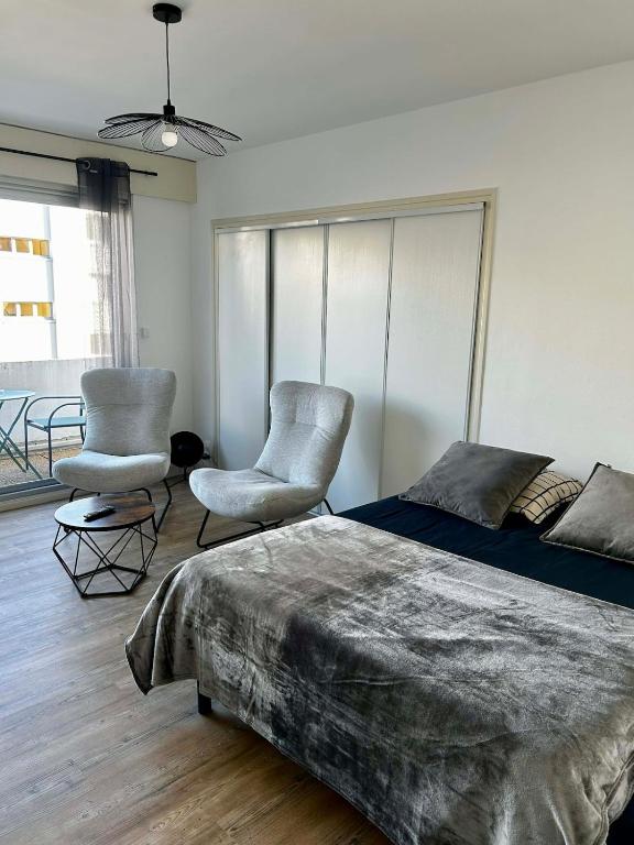 a bedroom with a bed and two chairs at Appartement carmes in Aurillac