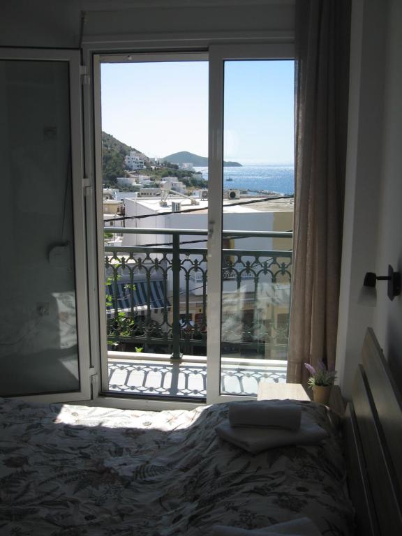a bedroom with a view of the ocean from a balcony at Platanos Rooms in Agia Marina