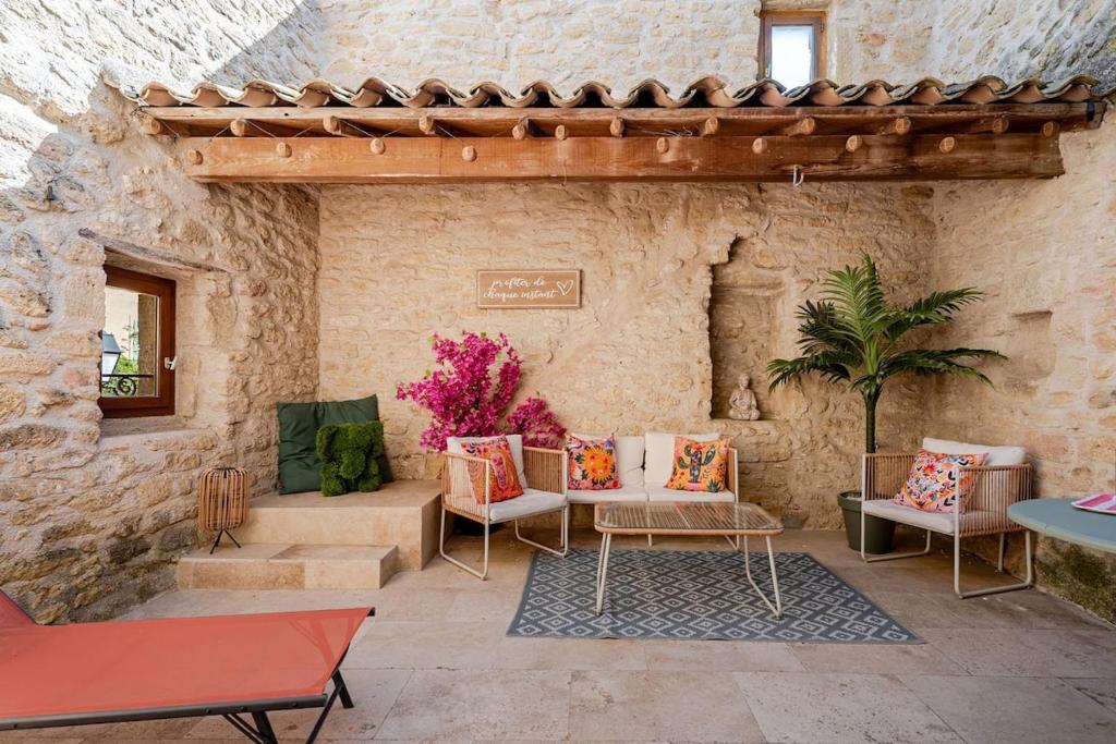 a patio with chairs and tables in a stone wall at Maison l’Oustaou Cornillonnais in Cornillon-Confoux