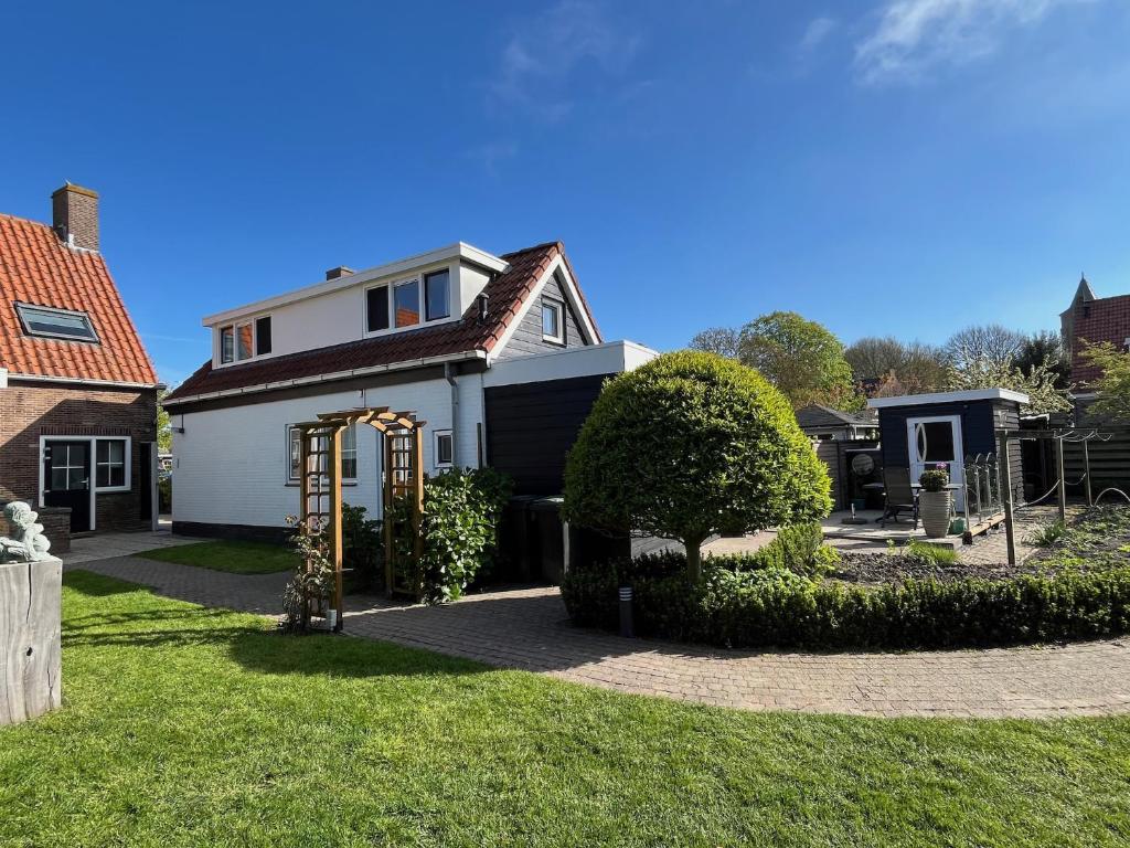 a white house with an arch in the yard at Pinkeltje in Aagtekerke