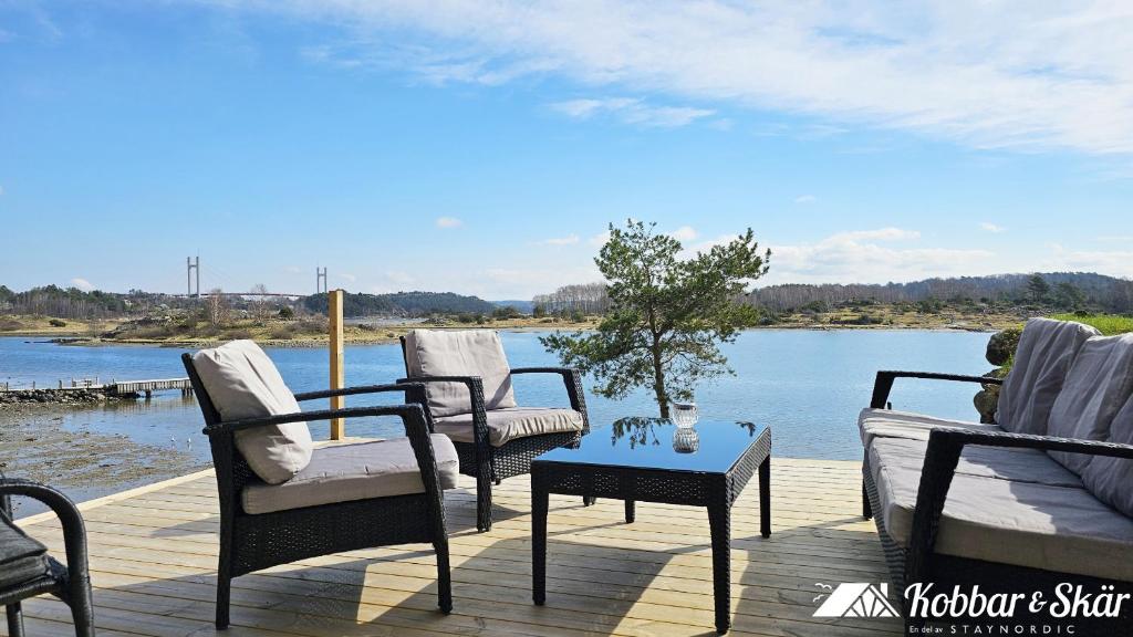 three chairs and a table on a deck next to the water at Cozy seaside cottage SE09169 in Myggenäs