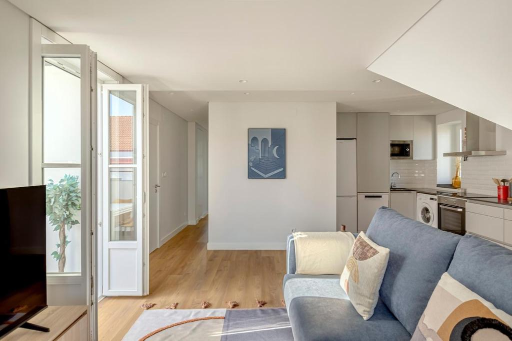 a living room with a blue couch and a kitchen at Casablanca 2BR Horizon in Caparica