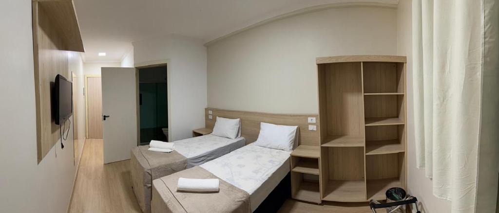 a small room with a bed and a shelf at Flat 55 Goiania in Goiânia