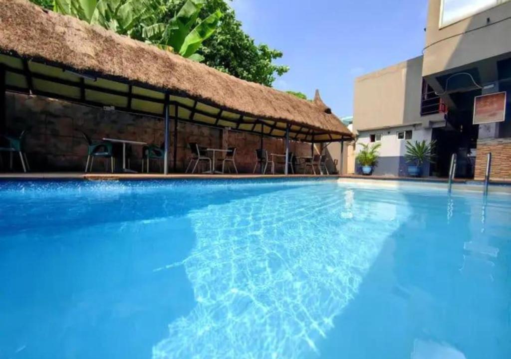 a large blue swimming pool with a thatch roof at Aotel Hotel Lagos Owodunni in Ikeja