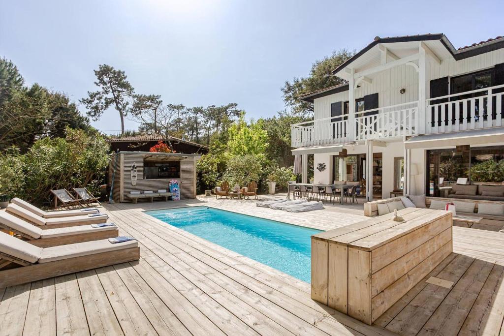a home with a swimming pool and a house at Villa Lilas Cap-Ferret in Lège-Cap-Ferret