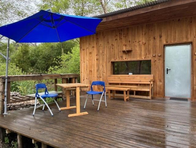 a wooden deck with a table and chairs and an umbrella at La Cabane du Bûcheron in La Teste-de-Buch