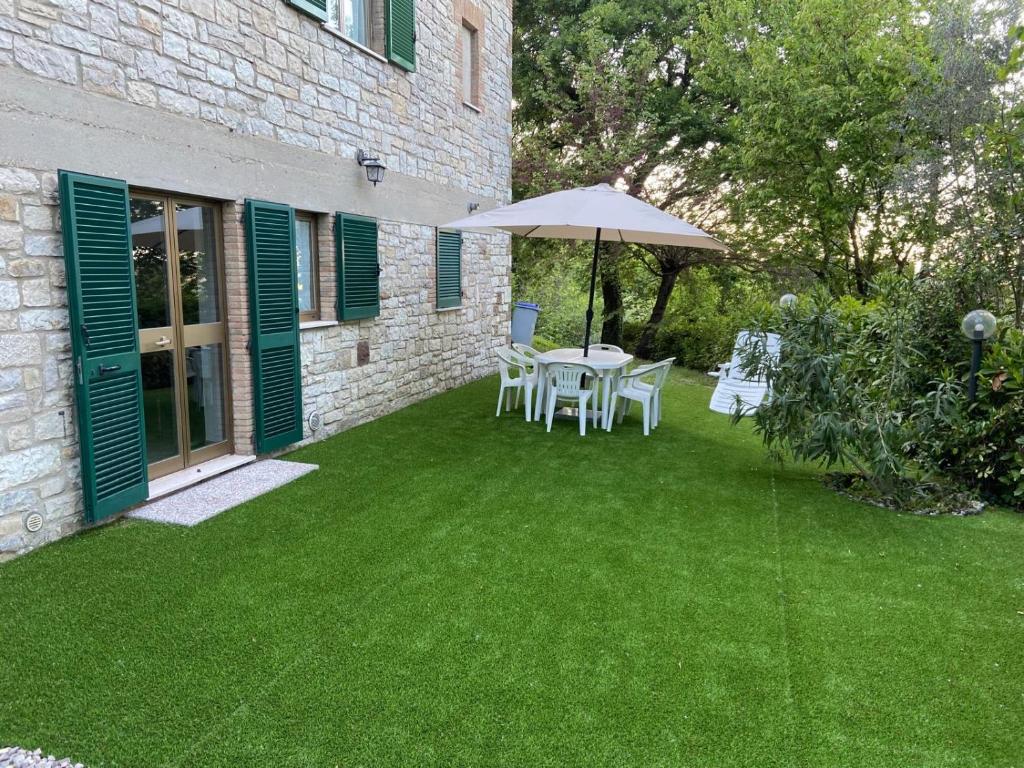 a patio with a table and an umbrella on a lawn at Casa Erica Todi in Todi