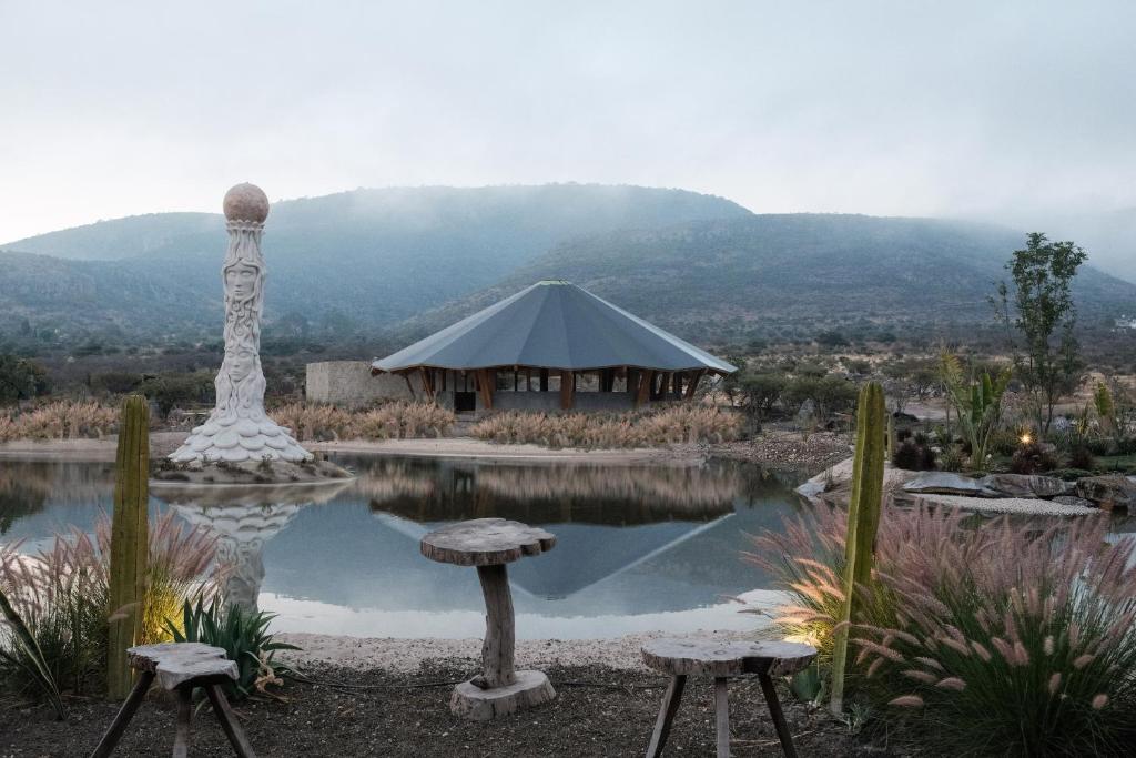 a tent and two stools in front of a pond at Casa X in San Miguel de Allende