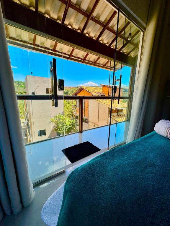a bedroom with a large window with a view of a building at Serra do Cipó Casa Baru in Santana do Riacho