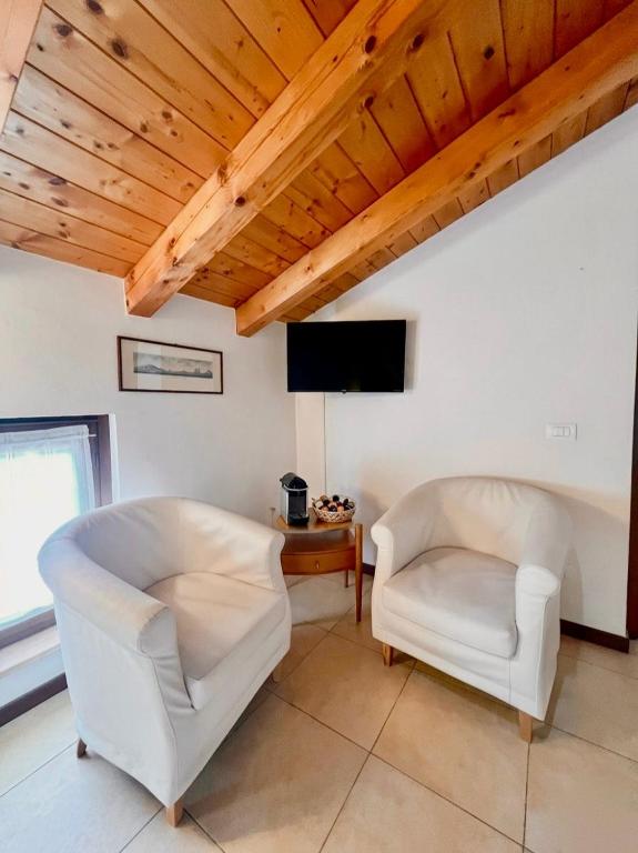 two white chairs in a living room with wooden ceilings at Welcome Traveller Caorsa Rooms in Cavaion Veronese