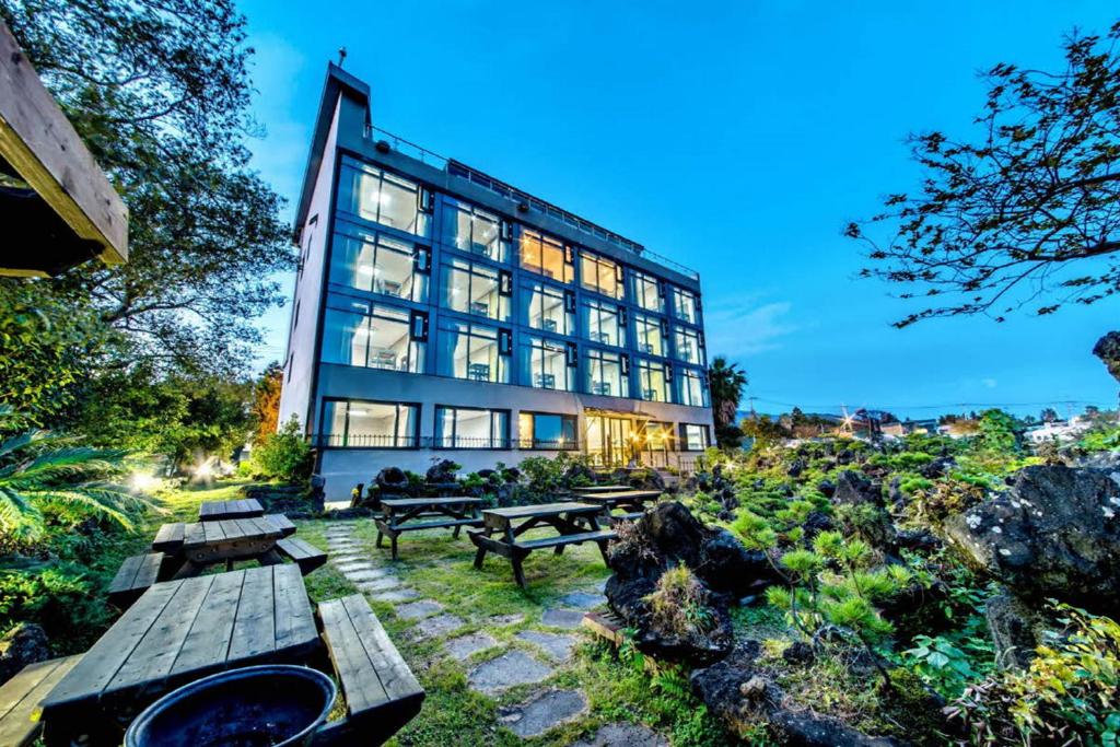 a building with picnic tables in front of it at Olleyo Resort in Seogwipo