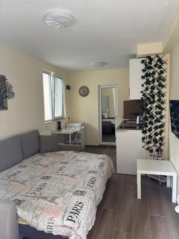 a bedroom with a large bed and a kitchen at Уют in Sandanski