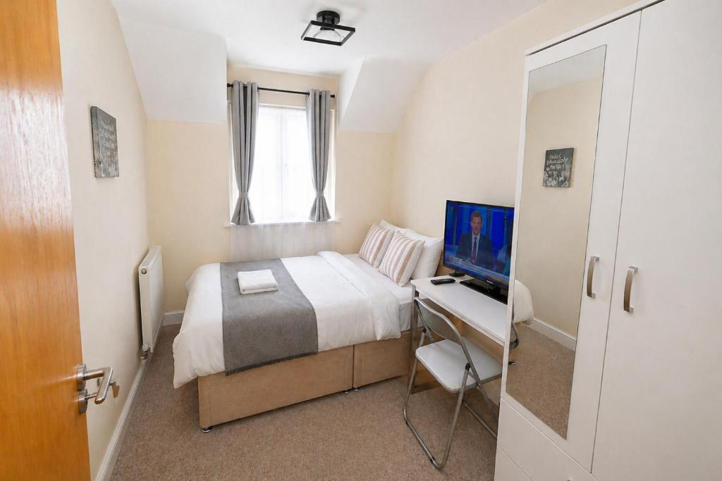 a bedroom with a bed and a desk with a television at Greenhithe Guest House in Stonewood
