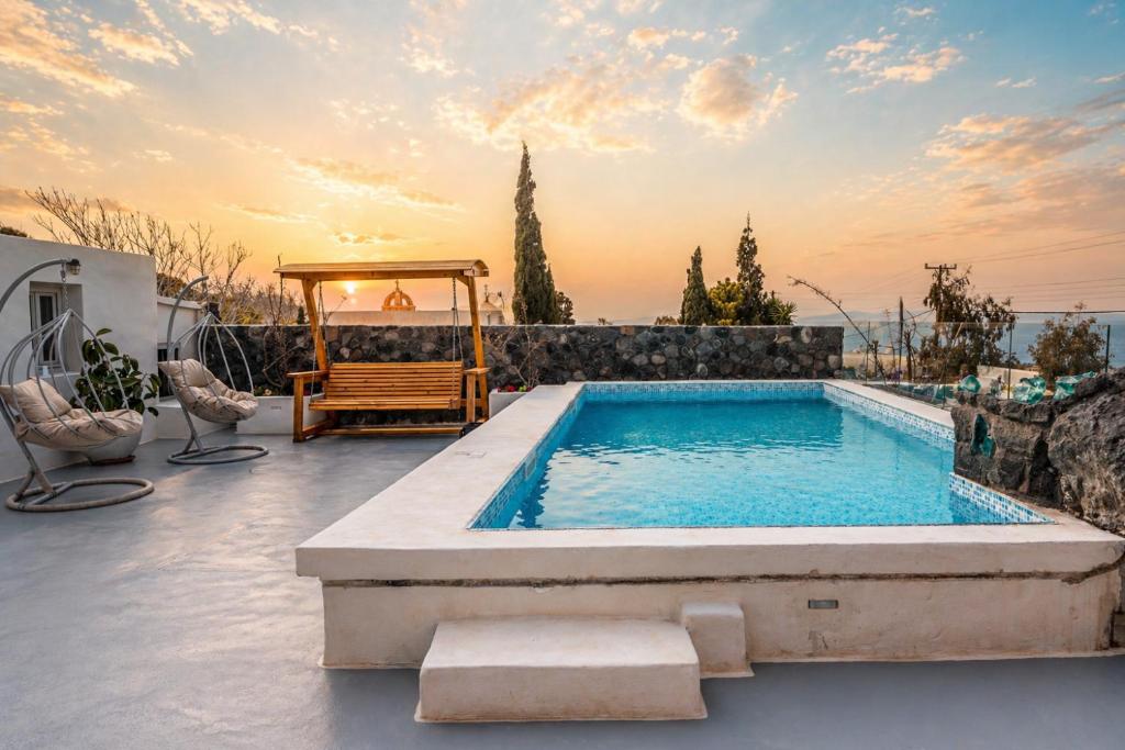 a pool in a backyard with a bench and a chair at Rody Caves Oia in Oia