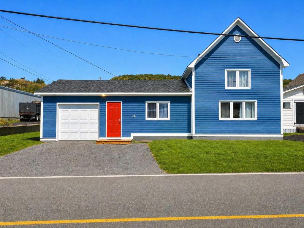 a blue house with a red door at Lands End Vacation Home in Twillingate