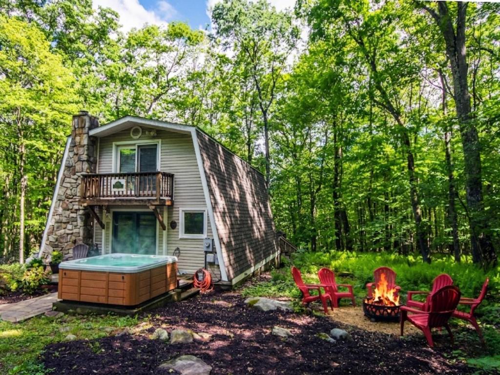 a tiny house in the woods with a hot tub and chairs at Owls Retreat in McHenry