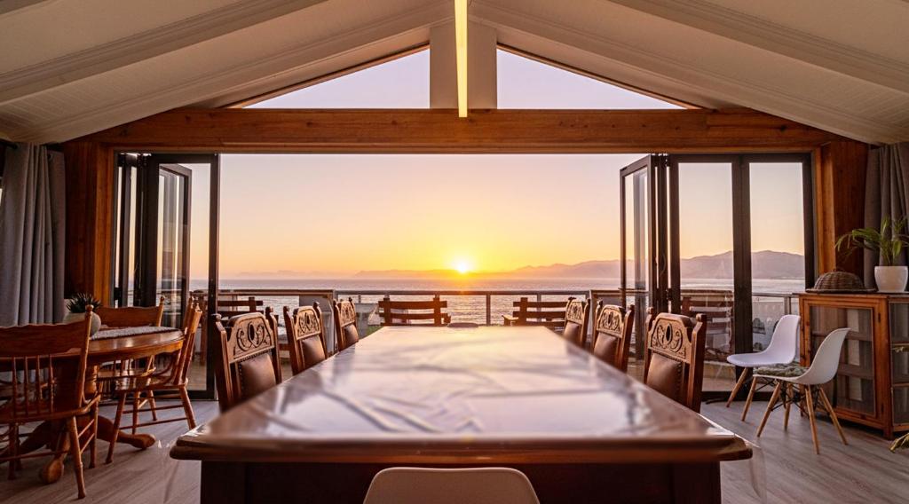 a dining room with a table and a view of the ocean at Whale Heights in De Kelders