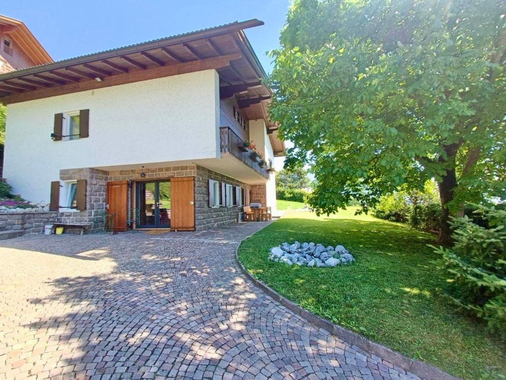 a house with a stone walkway in front of a yard at Villa ai noci in Carano