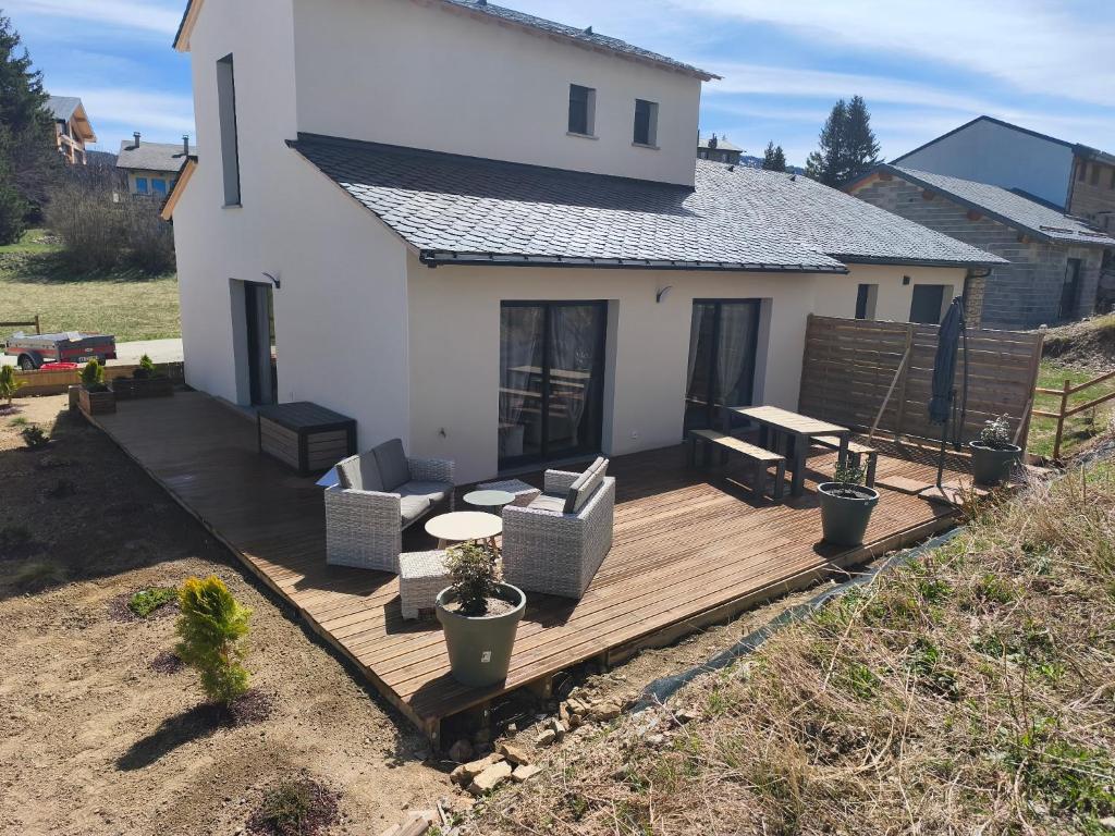 a wooden deck with furniture and a house at Maison familiale La Casa de la Cayote in Formiguères