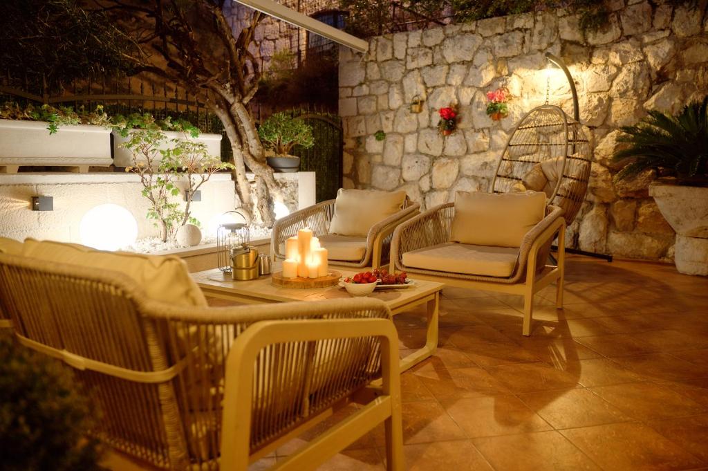 a patio with chairs and a table and a stone wall at Heritage House Pjaca, Omiš in Omiš