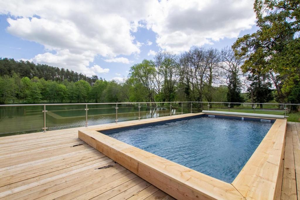a swimming pool on a deck next to a body of water at Gîtes BEAUSOLEIL in Campsegret