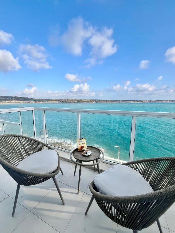 two chairs and a table on a balcony with the ocean at Very nice place by the sea in Is-Sellum