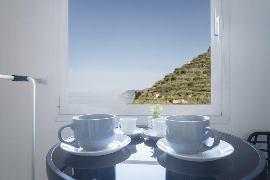 three cups and saucers on a table in front of a window at Cinque Terre, Sea View Home in Manarola