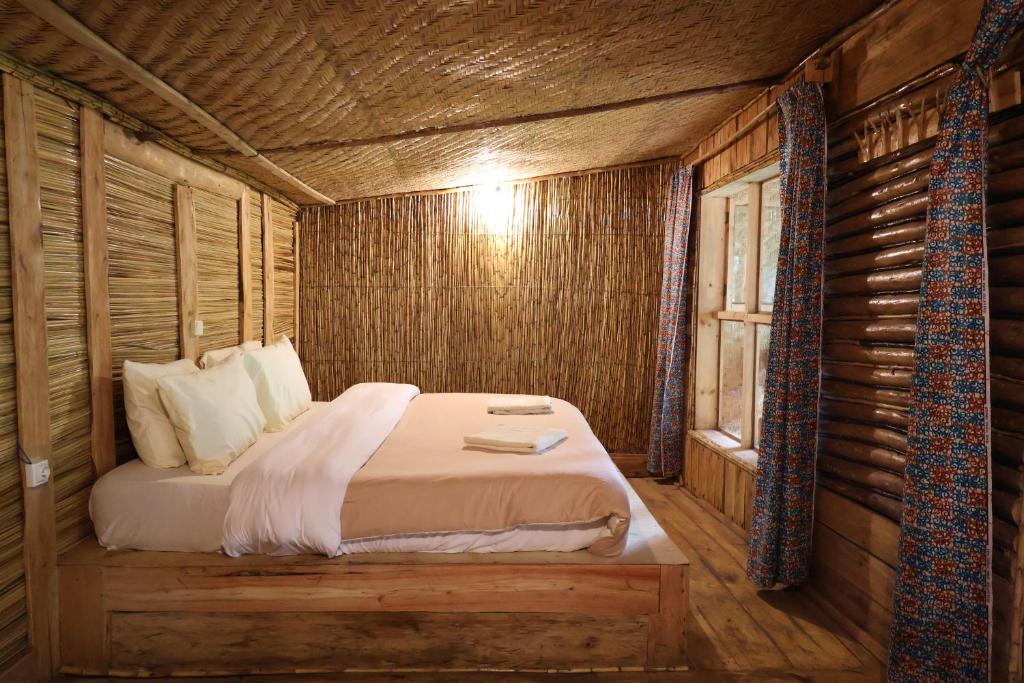 a bedroom with a bed in a log cabin at Noble Cheer in Ruhengeri