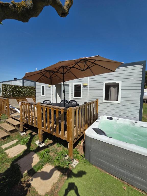 a hot tub with an umbrella in a yard at camping la plage de l'orb in Cessenon